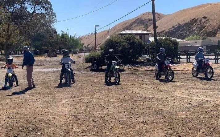 An instructor supporting students on their dirt bikes at Carnegie